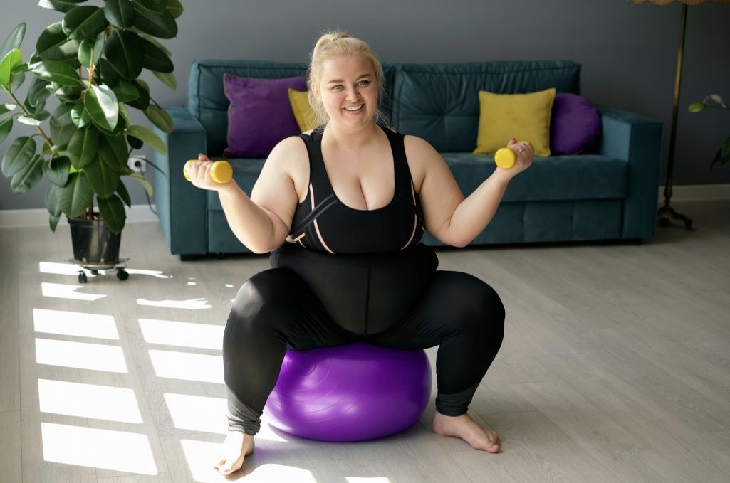 Woman exercising on yoga ball with weights.