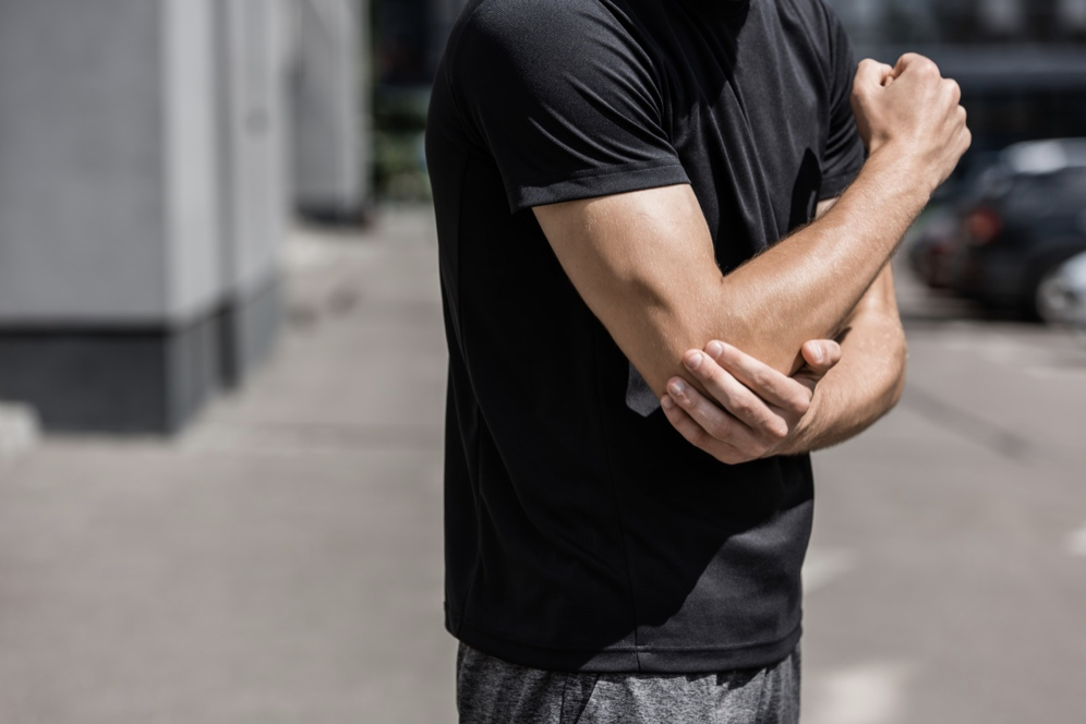cropped view of sportsman in black t-shirt with elbow pain on street