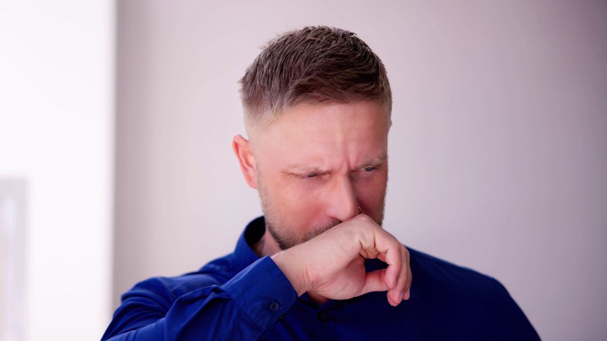 A Man in A Blue Shirt Covering His Mouth